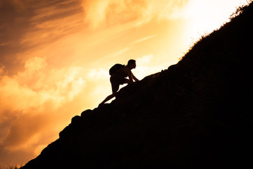 man hiker climbing up a steep mountain cliff. people taking risk, motivation and outdoor adventure c