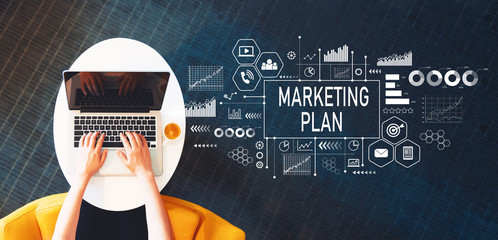 Wall Mural - Marketing Plan with person using a laptop on a white table