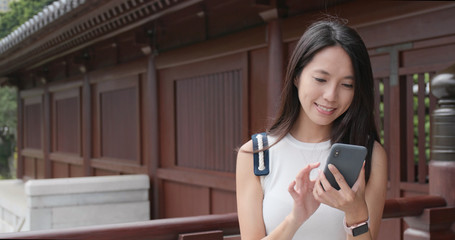 Wall Mural - Woman using mobile phone in traditional Chinese garden