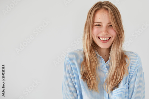 Fotografie, Obraz Joyful pretty young woman giggles positively at camera, dressed in casual shirt,