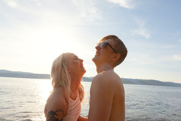 Wall Mural - Happy couple in love laughing at the beach against sun