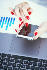 Businesswoman hand holds a new smartphone. The mobile application market shows a display you can insert your image for advertising or financial statistics.