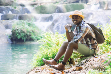 Wall Mural - African Man Traveller with backpack  smiling with happy in the green natural background.