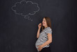 © .shock - pregnant woman thinking in front of black chalkboard