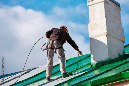 Worker of Industrial Alpinist Services painting roof in ...