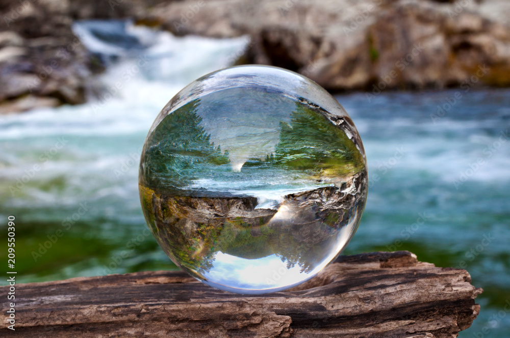 Crystal glass ball sphere reveals waterfall landscape with spherical perspective - obrazy, fototapety, plakaty 