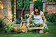 © cherryandbees - mid age woman with her dog doing some gardening in backyard