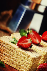 Wall Mural - Traditional russian honey cake decorated with strawberries and green mint, old wooden background, selective focus