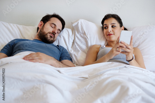 Cheating Wife Using Mobile Phone Lying In Bed Next To His Sleeping Husband Relationship Difficulties Stock Photo Adobe Stock