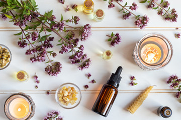 Wall Mural - Bottles of essential oil with blooming oregano, frankincense and other herbs