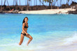 © Maridav - Hawaii beach vacation Asian bikini woman having fun splashing water waves in blue ocean at tropical travel destination. Young girl in black swimsuit playing in sea.