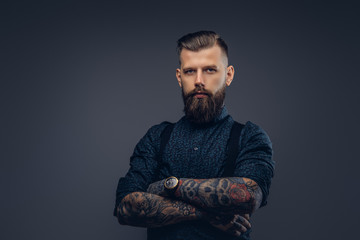 Wall Mural - Handsome old-fashioned hipster in shirt and suspenders, pose with crossed arms. Isolated on a dark background.