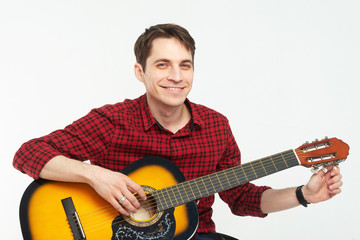 Cute young male musician in red shirt playing guitar.