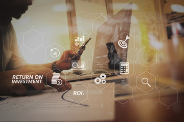 Poster - business man hand working on laptop computer with digital layer business graph information diagram on wooden desk as concept