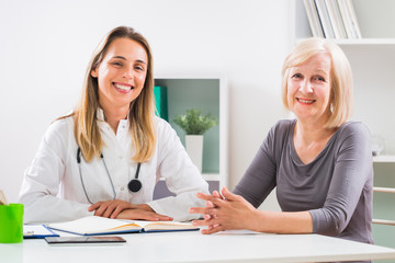 Wall Mural - Portrait of female doctor and senior woman patient sitting in doctor's office.