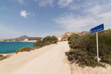 Colourful rocks of Firiplaka beach on Milos island, Greece. Road sign indicating way to the beach.