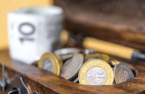 Fotografía Vintage wooden box full of money: rolled up Polish zloty banknotes and coins in a chest on wooden surface