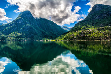 Wall Mural - Norway landscapes. The mountains are reflecting in the water of the fjord on a sunny day