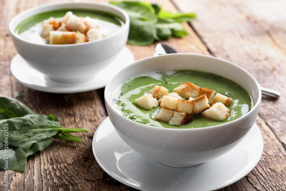 Bowls with delicious spinach soup on table