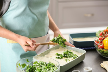 Woman cooking spinach lasagna in kitchen