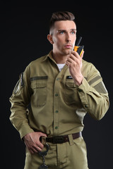 Wall Mural - Male security guard using portable radio transmitter on dark background