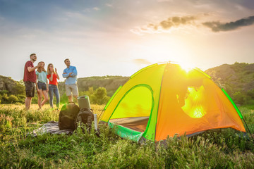 Wall Mural - Camping gear and group of young people in wilderness