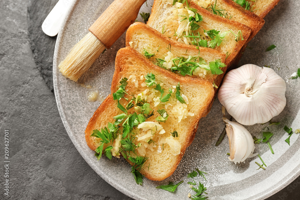 Plate with delicious homemade garlic bread on table
