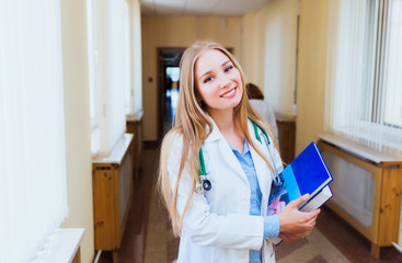 Young Asian doctor woman reading book with stethoscope on her shoulder on the background of patient room in the hospital