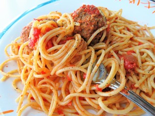 Cooked spaghetti with tomato sauce and meatballs on a dinner plate