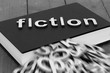 © Christian - Book novel with the word fiction and blurred letters coming out of the pages on a wood background