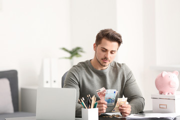 Poster - Young man counting money at table indoors