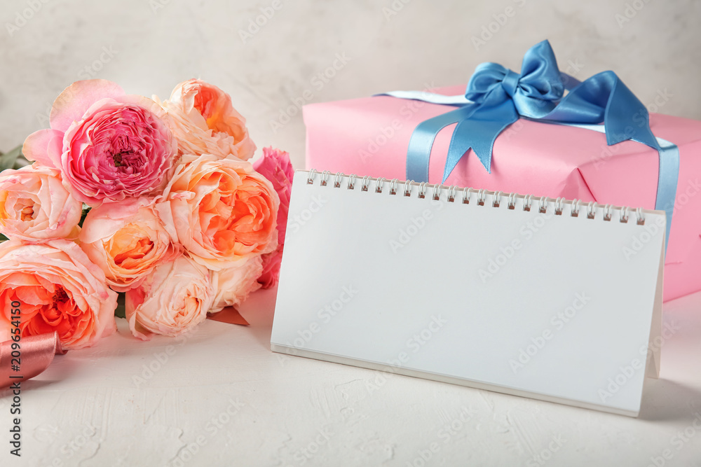 Beautiful flowers, blank calendar and gift box on table