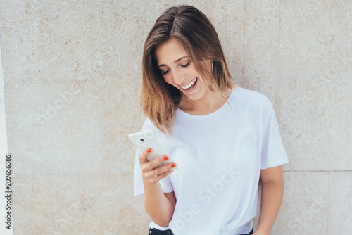 Foto junge frau lacht und schaut auf ihr smartphone