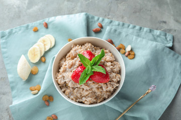 Bowl with tasty oatmeal and strawberry on napkin