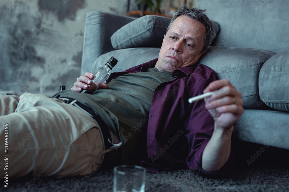 cigarettes and fatigue Photo Stock Smoking man. Drunk exhausted man looking not pleasant at all  while smoking cigarette lying on the floor