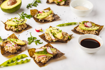 Canvas Print - Brown rice, avocado, peas nori wraps with soy sauce and tahini dressing on a white marble background.