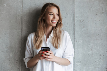 smiling young girl in sweatshirt holding mobile phone
