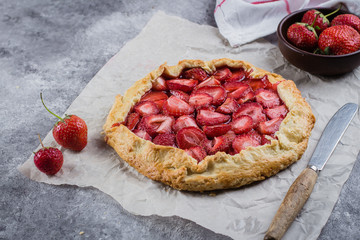 Wall Mural - Delicious summer food dessert. Galette with strawberry on the gray concrete stone background.