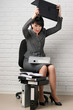 © soleg - angry business woman with laptop and folders having stress, dressed in a gray suit poses in front of a white wall