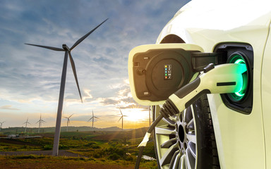 Wall Mural - EV Car or Electric car at charging station with the power cable supply plugged in on wind mill farm. The concept of renewable energy and environmentally friendly.	