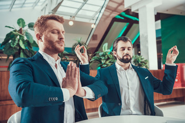 Wall Mural - Two worker men meditating at desk in office.