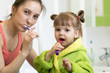 © Oksana Kuzmina - Happy mother and kid daughter brushing their teeth at home in the bathroom