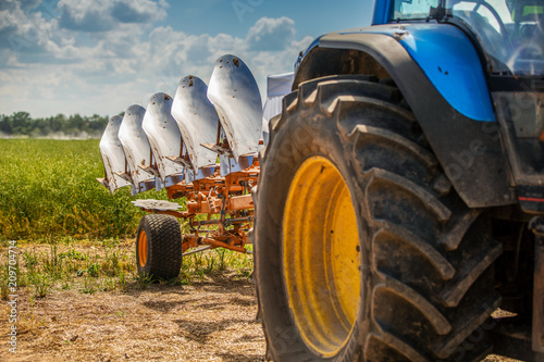 Fotografía tractor with plough beside the field