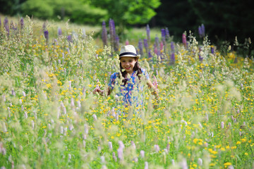 Wall Mural - Ein Mädchen steht in einer wilden Blumenwiese im Thüringer Wald