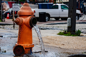 Street orange hydrant spreading water on the street