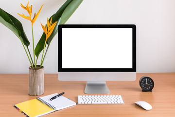 All in one computer, mouse, keyboard, clock, notebook, pen and flowers vase  on wooden table