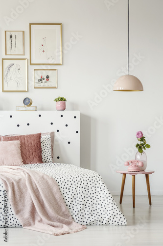 Fotografía Pink, old-fashioned phone on a wooden side table and a pendant lamp in a serene