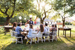 © Halfpoint - Bride and groom with guests at wedding reception outside in the backyard.