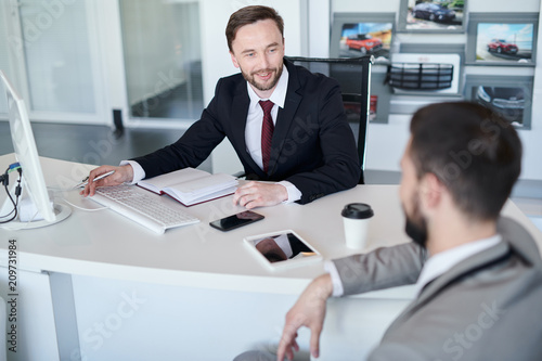 Fotografía Portrait of bearded handsome sales manager talking to client while sitting at de