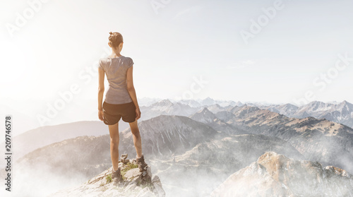 Fotografía Frau steht auf einem Berggipfel am Morgen